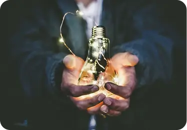 Hands holding a glowing lightbulb